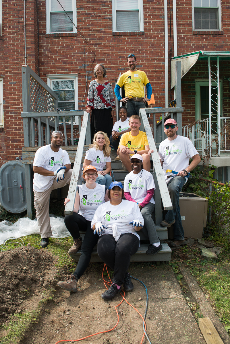 A group of Rebuilding Together volunteers and neighbors gathered on the front steps of a home